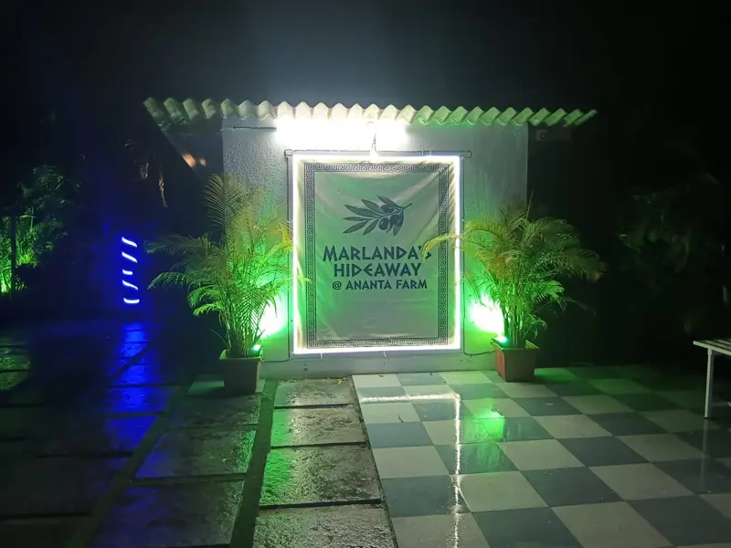 The Marlanda's Hideaway sign lit among the plants at night
